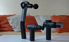 Best massage gun - Three massage guns lined up on a white table in front of a sofa
