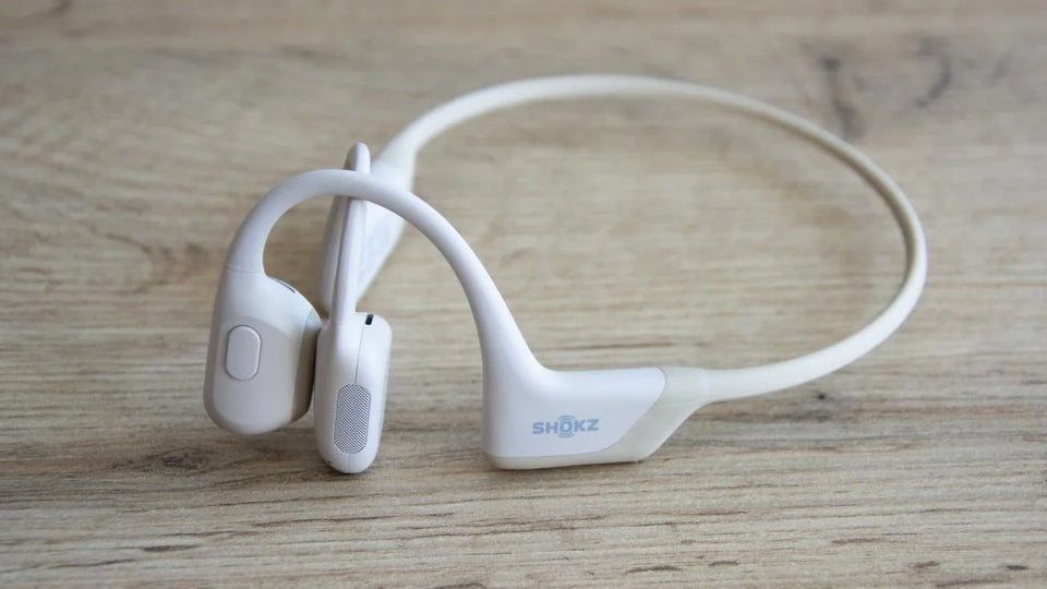 White Shokz OpenRun Pro headphones sitting on a desk 